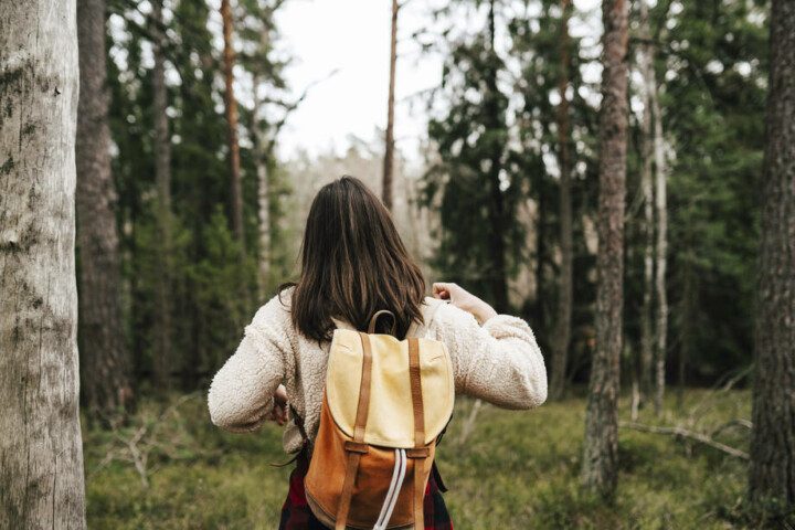 koululainen kävelee metsässä reppu selässään