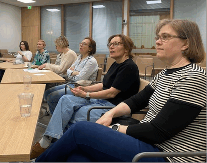 Kuusi henkilöä istumassa pöydän ääressä.